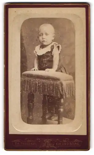 Fotografie Th. Thuesböl, Kalundborg, Storegade No 108 b, Kleinkind auf dem Sofa