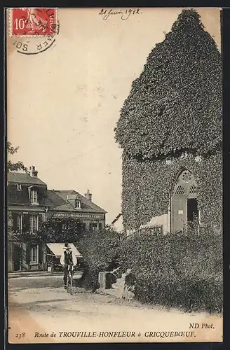 AK Cricquebœuf, Mann fährt Fahrrad auf einer Strasse im Ort