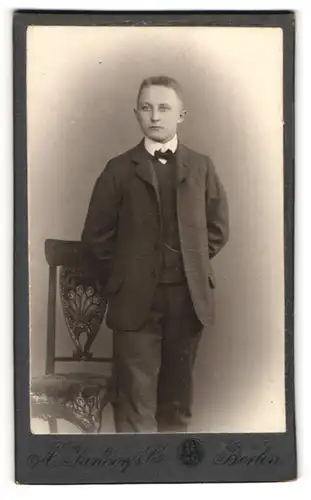 Fotografie A. Jandorf & Co, Berlin, Spittelmarkt 16, Junger eleganter Mann in dunklem Anzug mit Fliege und Segelohren