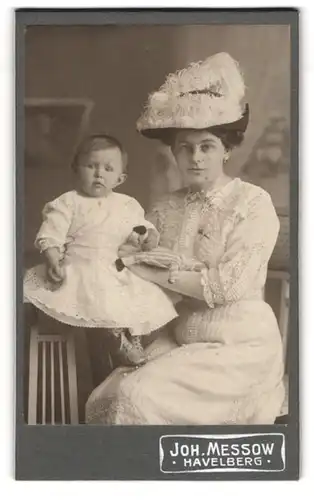 Fotografie Joh. Messow, Havelberg, Junge Mutter in weissem Kleid mit grossem Hut und niedlichem Baby mit Puppe