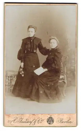 Fotografie A. Jandorf & Co, Berlin, Spittelmarkt 16, Schwestern in schwarzen taillierten Kleidern mit Buch und Rose