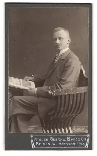 Fotografie Geschw. Baruch, Berlin, Mohrenstr. 63, Herr im grauen Anzug und gemusteter Krawatte liest Zeitung