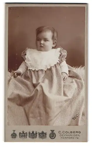 Fotografie C. Colberg, Oeynhausen, Klosterstr. 13, Niedliches Baby mit dicken Wangen im gestreiften langen Kleid
