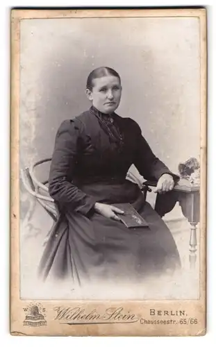 Fotografie Wilhelm Stein, Berlin, Chausseestr. 65, Dame mit fragendem Blick in schwarzem Kleid und Brosche