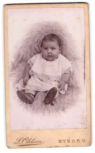 Fotografie L. Ohlsen, Nyborg, Kongegade 22, Niedliches Baby in weissem Kleid mit erschrockenem Blick