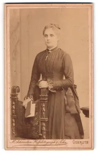 Fotografie M. Ackermann, Goerlitz, Schützenstrasse 2, Junge Dame in schwarzem Kleid mit silberner Kreuzkette