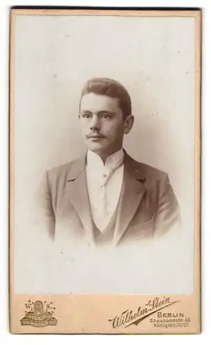 Fotografie Wilhelm Stein, Berlin, Chausseestr. 66, Junger Mann mit Schnurrbart in weissem Hemd mit breiter Krawatte