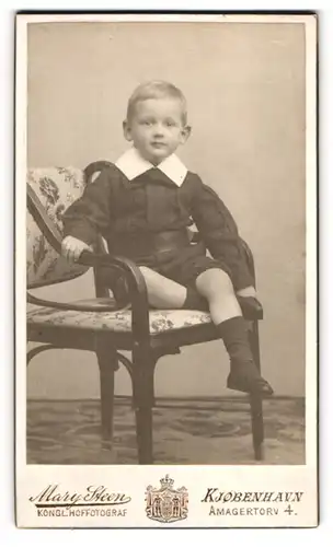 Fotografie Mary Steen, Kjöbenhavn, Amagertorv 4, Hübscher Junge mit verschmitztem Blick posiert sitzend auf einem Stuhl