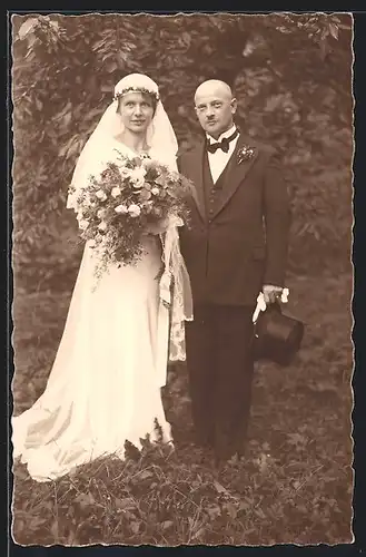 AK Hochzeitspaar in Brautkleid und Smoking, Blumenstrauss und Zylinder in den Händen