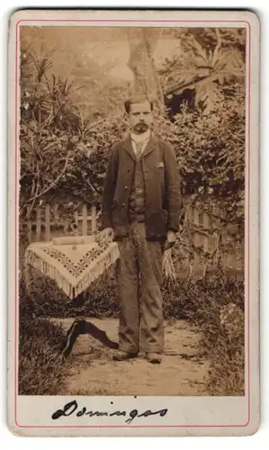 Fotografie unbekannter Fotograf und Ort, Portrait modisch gekleideter Herr an Gartentisch gelehnt