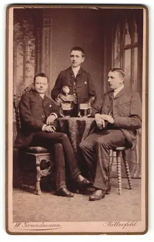 Fotografie W. Grundmann, Bitterfeld, Portrait drei bürgerliche Herren mit Bierkrügen am Tisch