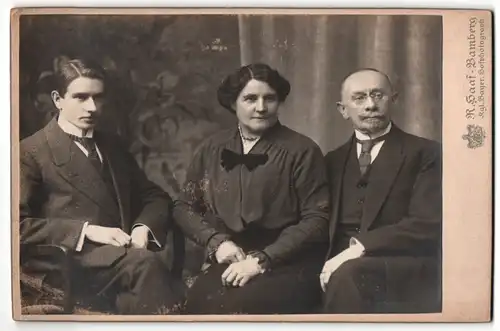 Fotografie R. Haaf, Bamberg, Dame mit dunklen Haaren und Herr mit Brille sitzen neben jungem Mann