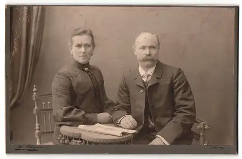 Fotografie Hans Ohrner, Blumenthal i/Han., Herr mit Schnauzbart und Taschenuhr sitzt an Tisch mit Frau in dunkler Bluse