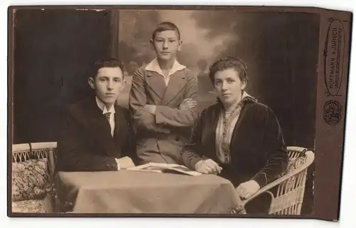 Fotografie Hoffmann & Jursch, Leipzig, Zwei junge Burschen neben am Tisch sitzender Mutter in dunklem Kleid