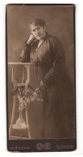 Fotografie J. Fuchs, Berlin-Schöneberg, Portrait bürgerliche Dame mit Blumen an Tisch gelehnt