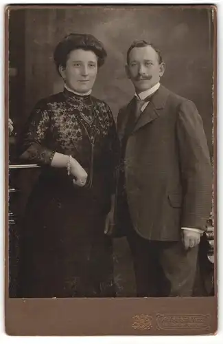 Fotografie August Lutz, Gera, Portrait hübsch gekleidetes Paar an Tisch gelehnt
