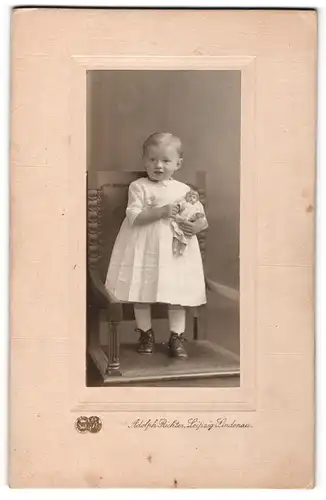 Fotografie Adolph Richter, Leipzig-Lindenau, Portrait kleines Mädchen im weissen Kleid mit Puppe