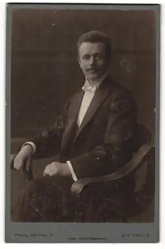 Fotografie Paul Heinelt, Zittau i. S., Portrait sitzender Herr im Anzug mit Flliege