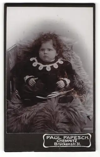 Fotografie Paul Papesch, Chemitz, Portrait niedliches Mädchen mit lockigem Haar auf Fell sitzend