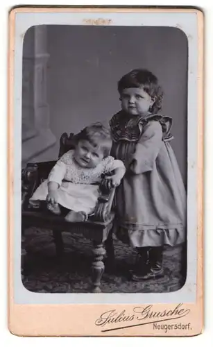Fotografie Julius Grusche, Neugersdorf i. / Sachs., Portrait kleines Mädchen im hübschen Kleid mit Kleinkind