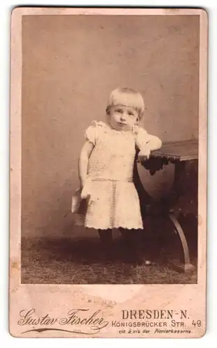 Fotografie Gustav Fischer, Dresden-N., Portrait kleines Mädchen im hübschen Kleid am Tisch lehnend