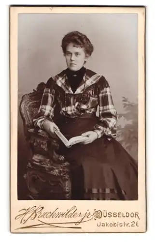 Fotografie H. Bruckwilder jr., Düsseldorf, Jakobistrasse 26, Junge Dame mit Buch in einem Stuhl