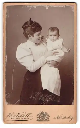 Fotografie Hermann Krull, Neustrelitz, Junge Frau in weisser Bluse mit einem Baby
