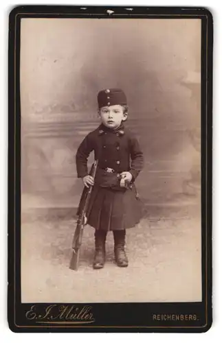 Fotografie Ernst J. Müller, Reichenberg / Liberec, kleines Mädchen als Soldatin mit Säbel und Gewehr bei Fuss