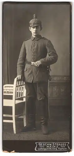 Fotografie Geschw. Strauss, Mainz, junger Soldat in Feldgrau Uniform mit Pickelhaube Tarnbezug