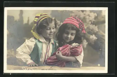 AK Kinderpaar mit Zipfelmützen spielt mit einer Puppe