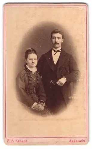 Fotografie P. P. Hansen, Apenrade, Bürgerliches Paar in dunkler Kleidung mit Perlenkette und Taschenuhr