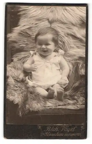 Fotografie Rich. Vogel, Glauchau i. S., Portrait süsses lachendes Kleinkind auf Fell sitzend