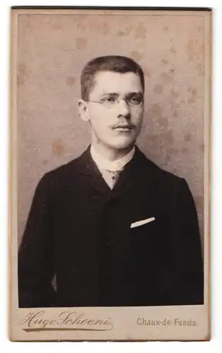 Fotografie Hugo Schoeni, Chaux-de-Fonds, Portrait junger Mann mit Brille im eleganten Jackett