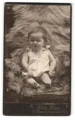 Fotografie Rich. Vogel, Glauchau i. S., Portrait niedliches Kleindkind im weissen Hemdchen auf Fell sitzend