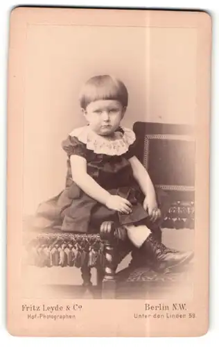 Fotografie Fritz Leyde & Co., Berlin-NW, Portrait kleines Mädchen im hübschen Kleid auf Tisch sitzend