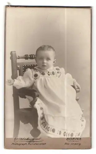 Fotografie Emil Schuffert, Borna i / S., Portrait süsses Baby im hübschen Kleid im Hochstuhl sitzend