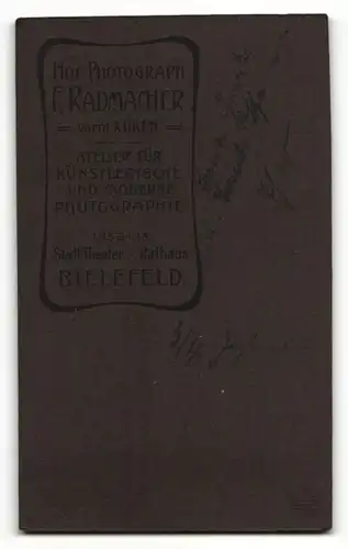 Fotografie F. Radmacher, Bielefeld, Portrait süsses Kleinkind im weissen Kleid auf Tisch sitzend