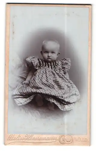 Fotografie Max Hennemann, Wald, Portrait süsses Kleinkind im karierten Kleid auf Fell sitzend