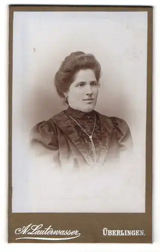 Fotografie A. Lauterwasser, Überlingen, Frau mit gelockten toupierten Haaren trägt dunkles Kleid und Halskette