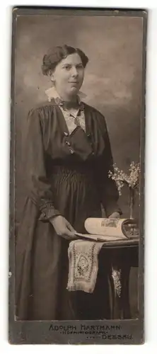 Fotografie Adolph Hartmann, Dessau, Portrait bürgerliche Dame mit Heft am Tisch stehend