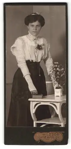 Fotografie C. Grosser, Limbach i. Sa., Portrait hübsch gekleidete Dame mit Buch am Tisch stehend