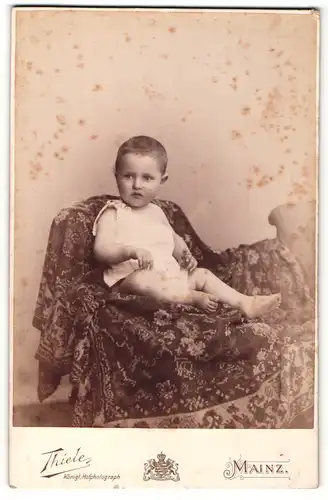 Fotografie Thiele, Mainz, Portrait niedliches Kleinkind im weissen Hemd auf Decke sitzend