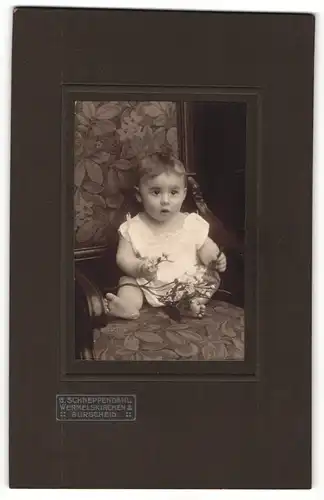 Fotografie G. Schneppendahl, Wermelskirchen, Portrait sitzendes Kleinkind im weissen Hemd mit nackigen Füssen und Zweig