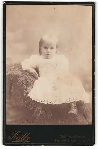 Fotografie T. Reilly, New York, Portrait niedliches Kleinkind im weissen Kleidchen