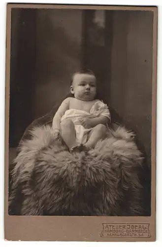 Fotografie Atelier Ideal, Hamburg-Barmbeck, Portrait niedliches Kleinkind im weissen Hemd auf Fell sitzend