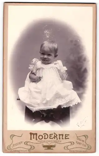 Fotografie Marius Christensen, Köbenhavn-K, Portrait sitzendes Kleinkind im weissen Kleid mit Schleifchen