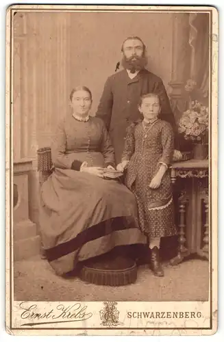 Fotografie Ernst Krebs, Schwarzenberg, Portrait bürgerliches Paar mit einer Tochter und Buch am Tisch
