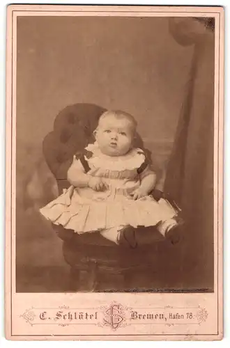 Fotografie C. Schlötel, Bremen, Portrait niedliches Kleinkind im hübschen Kleid mit Schleifchen