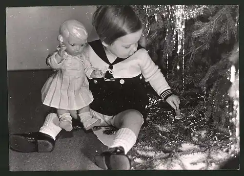 Fotografie Kleines Mädchen mit Puppe bei Weihnachtsbescherung