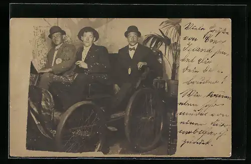Foto-AK Drei Herren auf einem zusammengeschusterten Auto in der Studiokulisse